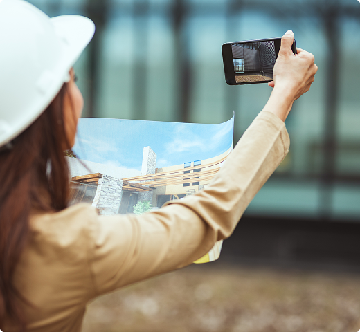 A female surveyor wearing a hard hat taking a picture with her phone